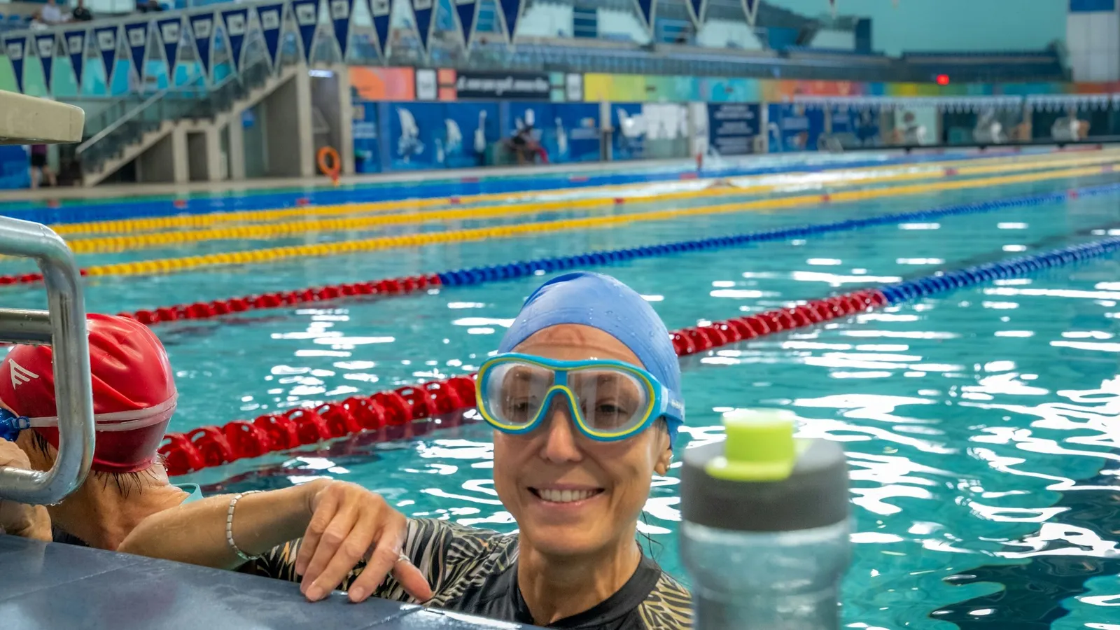 Uśmiechnięta pływaczka w goglach przy brzegu basenu sportowego